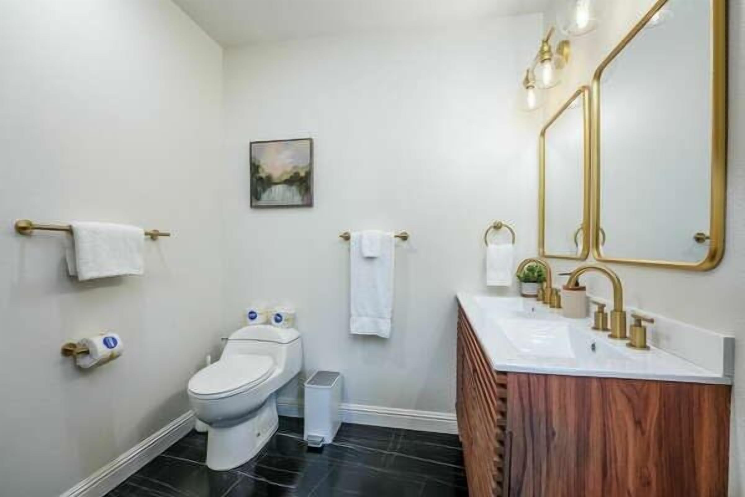 A modern bathroom with a toilet, sink, and mirror.