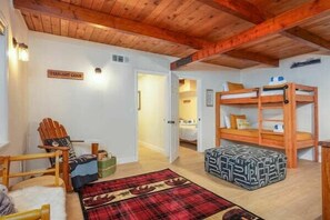 Interior acogedor de una cabaña con techo de madera, una cama litera, un tapete escocés y una silla.