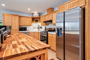 A modern kitchen with wooden cabinets, stainless steel appliances, and a built-in water dispenser.