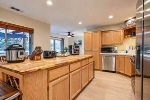 A modern kitchen with wooden cabinets, stainless steel appliances, and a large island.