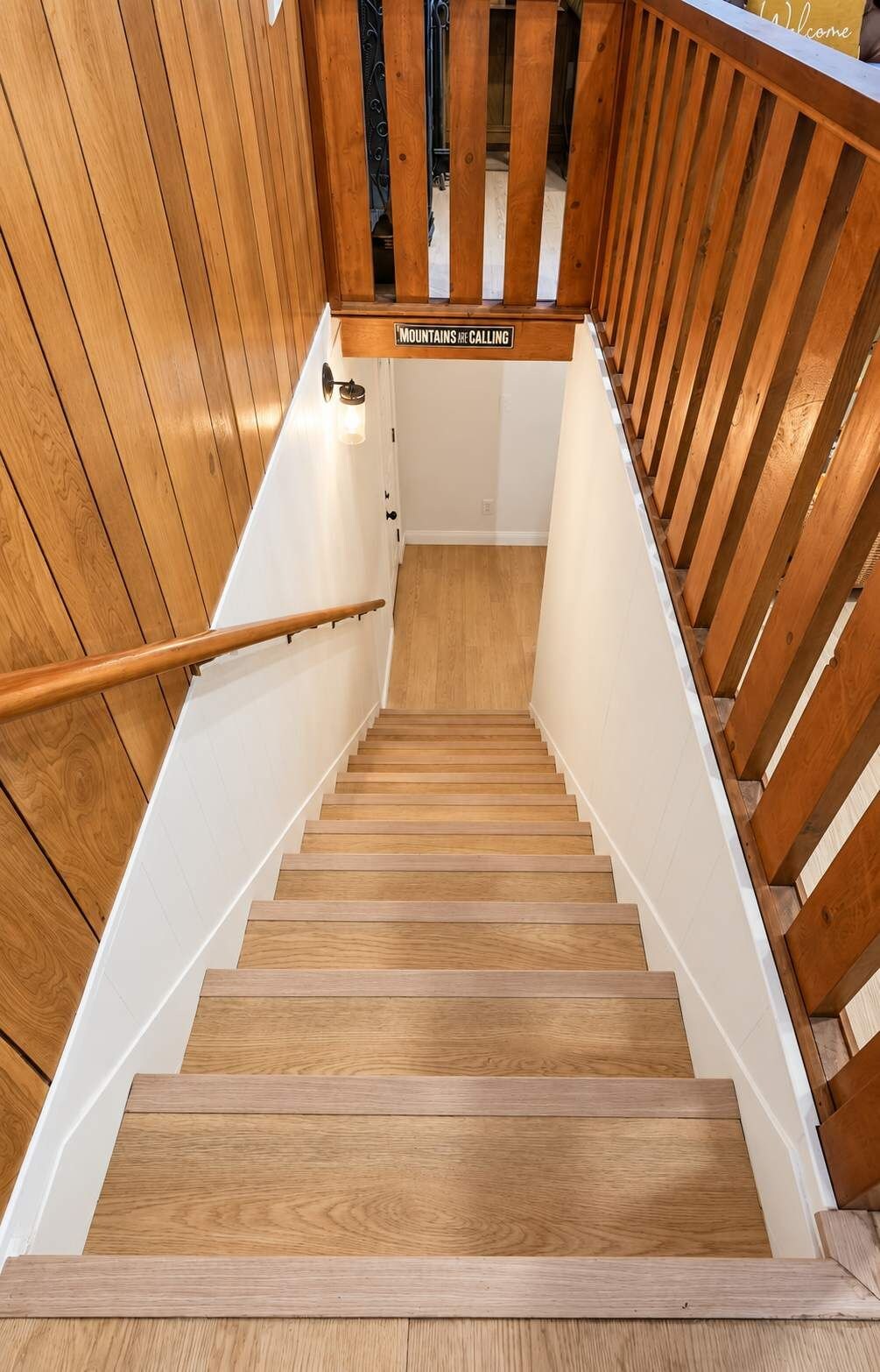 A wooden staircase with a handrail, leading to a landing with a sign that reads 'Mountains are calling.'