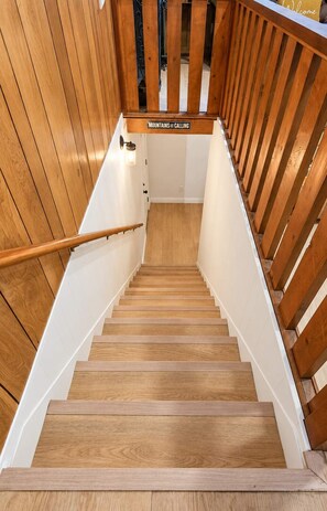A wooden staircase with a handrail, leading to a landing with a sign that reads 'Mountains are calling.' - Hot Tub & Game Room • Starlight Cabin Retreat (Oakhurst)