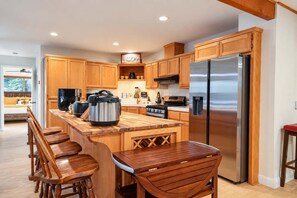 Een moderne keuken met houten kasten, een roestvrijstalen koelkast, een groot eiland met barkrukken en een inbouwoven.