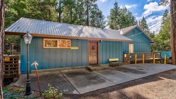 A small, single-story building with a blue exterior, a wooden door, and a bench outside.