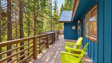 Une terrasse en bois avec une rambarde, une table et deux chaises.