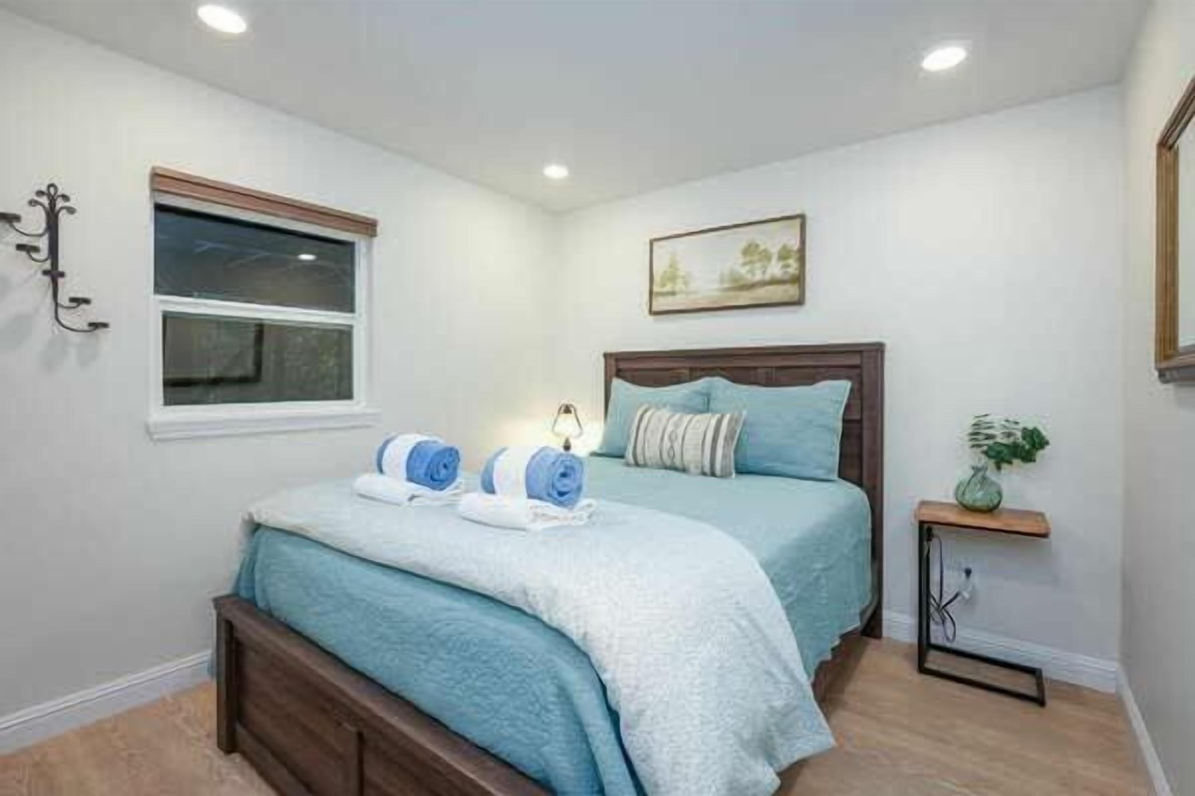 A bedroom with a bed, bedside tables, a window, and a wall-mounted picture.