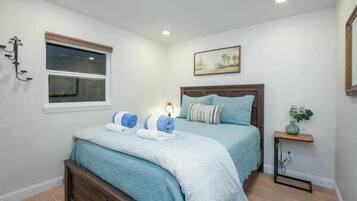 A bedroom with a bed, bedside tables, a window, and a wall-mounted picture.