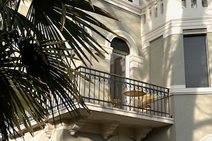 A balcony with a wrought iron railing, a small table, and a chair. - Villa Ada at the Lido (Venezia)