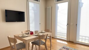 Uma sala de jantar com uma mesa, cadeiras e uma televisão na parede.