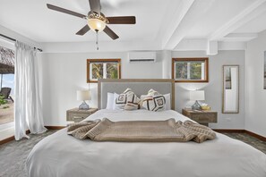Ein Hotelzimmer mit einem Bett, zwei Nachttischen, einem Deckenventilator, einem Fenster mit Blick und einer Wandklimaanlage.