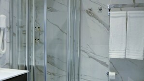 A modern bathroom with a glass shower enclosure, a white sink, and a marble wall. - Arsenale Turin Room 3 (Torino)