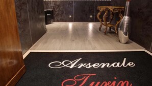 Vestíbulo de hotel con alfombra negra que presenta 'Arsenal' y 'Turin' en blanco y rojo.