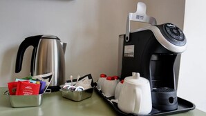 Una cafetera, un hervidor y una bandeja con tazas y condimentos sobre una mesa.