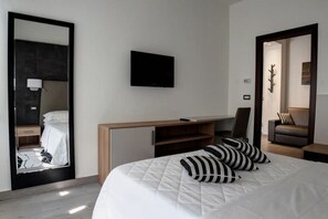 Una habitación de hotel moderna con cama, escritorio, televisor de pantalla plana y espejo.