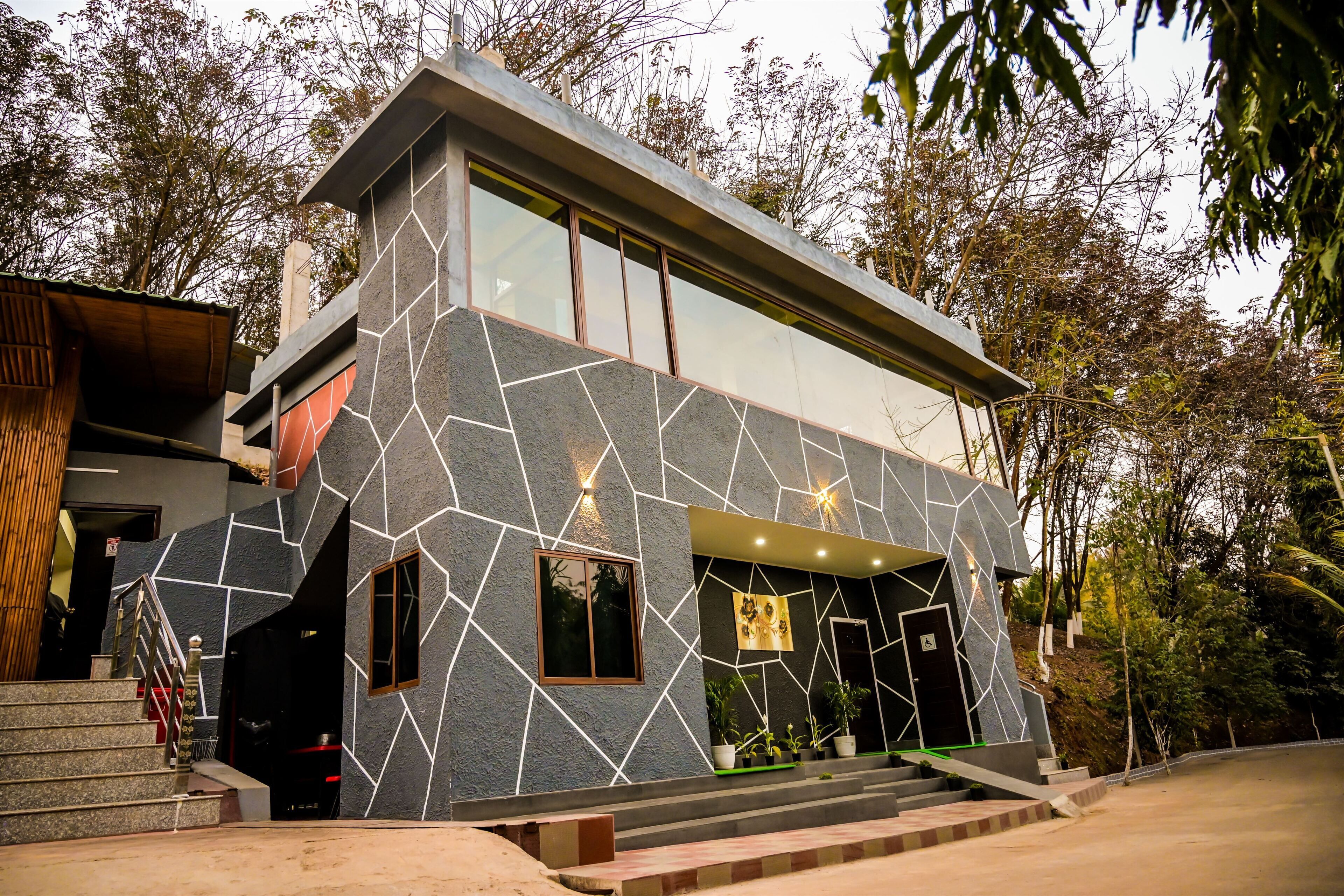 A modern building with a geometric stone facade, large windows, and a staircase leading to the entrance.