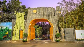 A large tree-like archway with a door, surrounded by potted plants and a signboard.