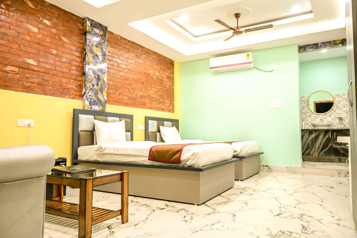 Une chambre d’hôtel comprenant un lit, une petite table, une chaise, un ventilateur de plafond et une salle de bain avec un miroir et un lavabo.