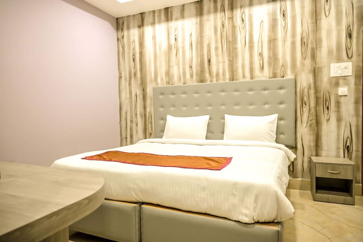 Une chambre à coucher bien rangée, avec un grand lit, une table de chevet et une petite commode.