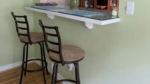 A kitchen with a white countertop, two bar stools, and a wooden cabinet with glass doors. - Spacious Home Away from Home (Columbus)