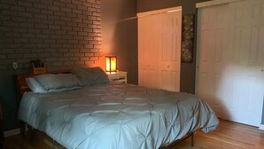 A bedroom with a bed, a nightstand, a lamp, and a door. - Spacious Home Away from Home (Columbus)