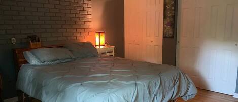 A bedroom with a bed, a nightstand, a lamp, and a door.