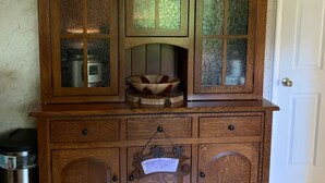 A wooden cabinet with multiple drawers and a central shelf, featuring frosted glass panels and a decorative metal sign. - Spacious Home Away from Home (Columbus)