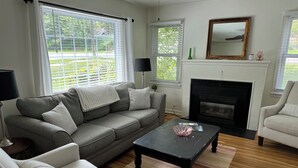 A living room with a grey sofa, a white armchair, a black coffee table, and a fireplace.