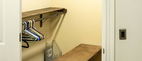 A room with a wooden bench, a metal table, and a clothing rack with hangers.