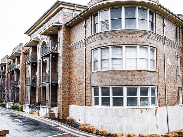 A corner building with a brick facade, multiple windows, and a curved section. - Located within the heart of the entertainment district! ADA ramp/parking on site (Fayetteville)