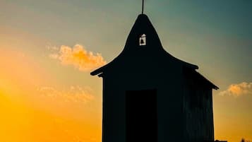 A small building with a cross on top, likely a church, with a clear sky in the background.