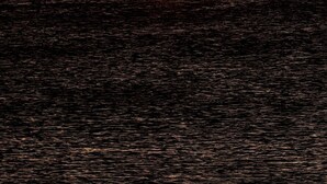 Um pôr do sol sobre a água, com um navio e uma construção pequena ao longe.