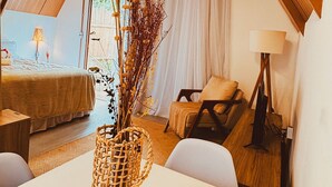Ein gemütliches Schlafzimmer im Loft-Stil mit schrägem Dach, einem großen Fenster und einem Essbereich mit einer Korbwäsche auf dem Tisch.