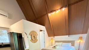 Habitación de hotel con cama, lámparas de noche, un reloj de pared, una mesita y una zona de estar.