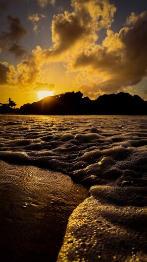 Ein Strandbild mit Wellen und einem Sonnenuntergang.