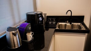 Uma cozinha compacta com cafeteira, chaleira e pia.