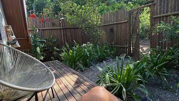 A wooden deck with a metal chair, surrounded by a wooden fence and lush greenery.