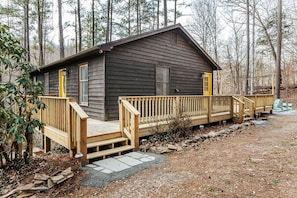 Eine Holzhütte mit einer Holzterrasse, einer Haustür und einer kleinen Veranda.