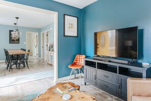 A living room with a large flat-screen TV, a wooden coffee table, and a blue accent wall.