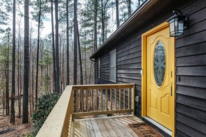 A wooden deck leading to a house with a yellow door and a window with a decorative glass design.