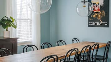 Un coin repas avec une table en bois et des chaises noires, un ventilateur de plafond et une affiche accrochée au mur.
