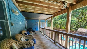 A covered porch with wicker furniture and a view of a swimming pool. - COOL AZUL - 5 bed, 3 bath pool home in Southern Shores, dog friendly (Southern Shores)