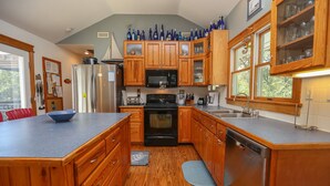 A kitchen with wooden cabinets, a stainless steel refrigerator, a microwave, and a dishwasher. - COOL AZUL - 5 bed, 3 bath pool home in Southern Shores, dog friendly (Southern Shores)