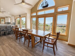 Cozinha espaçosa com uma grande mesa de jantar e cadeiras, piso de madeira e janelas amplas com vista.
