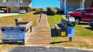 Un muelle de madera que lleva a una zona de playa privada con un letrero que indica prohibido el paso y acceso restringido a propietarios de águilas pescadoras e invitados.