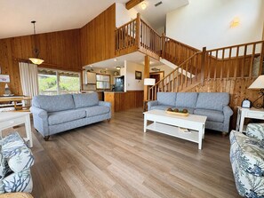 A spacious living area with two sofas, a coffee table, and a staircase leading to an upper level.