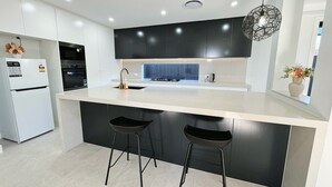 A modern kitchen with a large island, black bar stools, and a built-in oven.