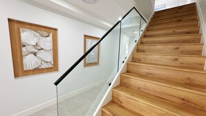 A staircase with wooden steps and glass railings, leading to an upper floor.