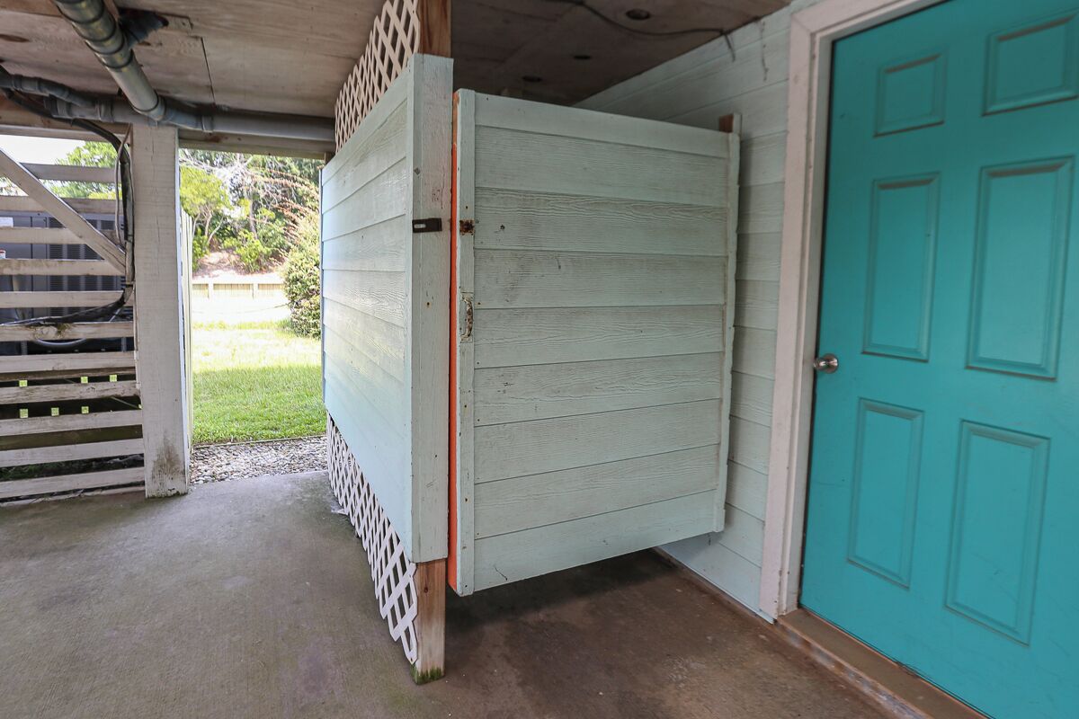 A room with a closed door, a white lattice fence, and a concrete floor.