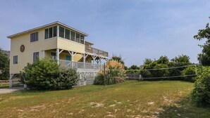 Ein zweistöckiges Gebäude mit Balkon, umgeben von einem Rasen und Büschen.
