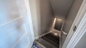 Un escalier étroit avec une rampe en bois et une porte sur le côté gauche.